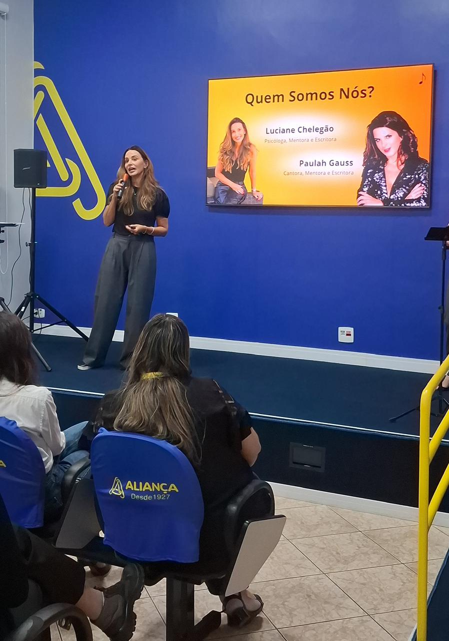 Luciane conduzindo palestra com apresentação Quem Somos Nós